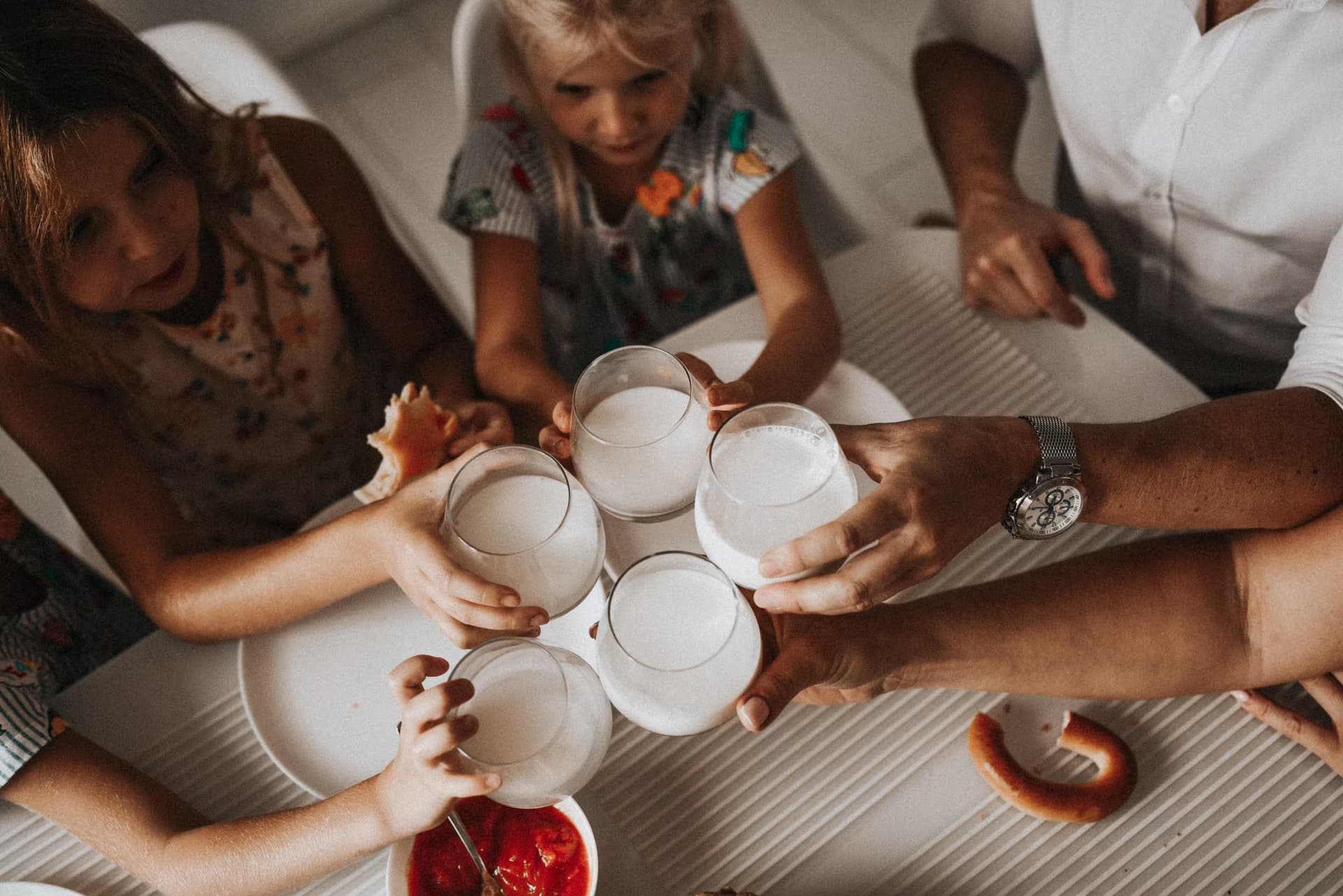 Overhead shot of a family clinking glasses of milk together around a table